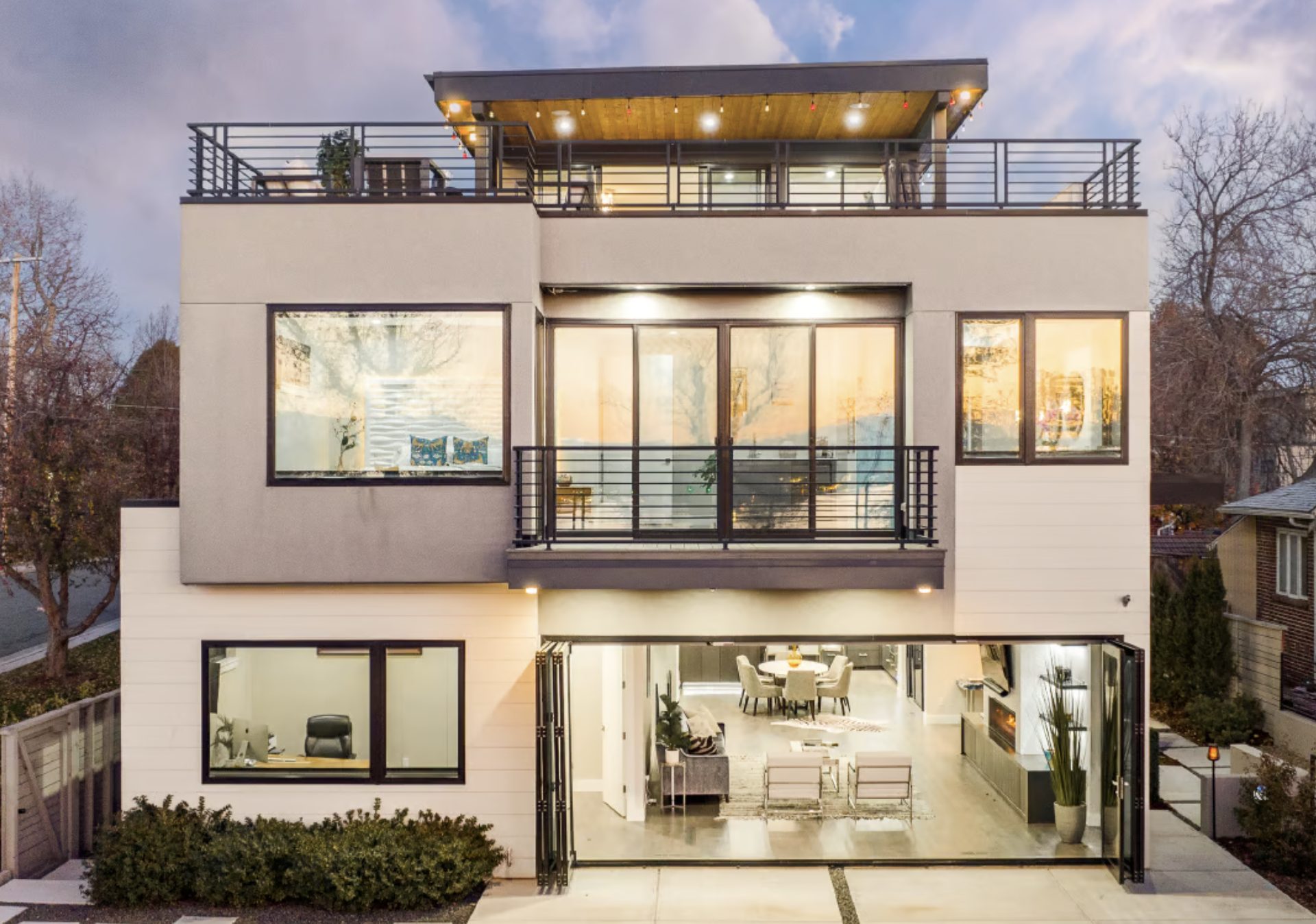 Contemporary three-story home near Sloan’s Lake with rooftop deck, folding glass doors, and open-concept luxury interiors at dusk.